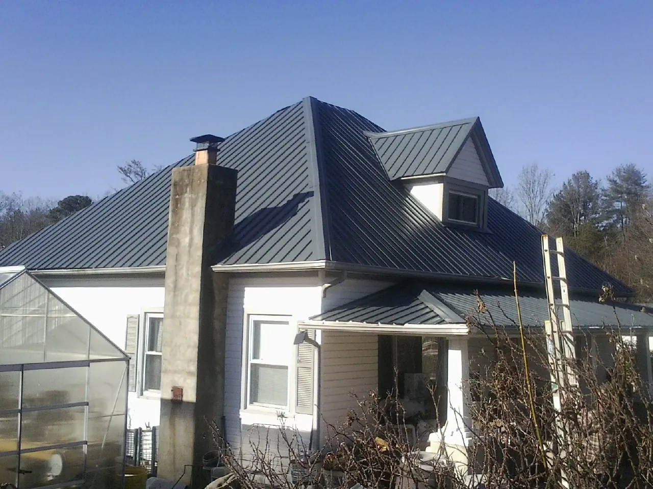 Dark blue standing seam metal roof on a white farmhouse with dormer — Slate & Tile Roof Repair by Roofing Brothers in Susan