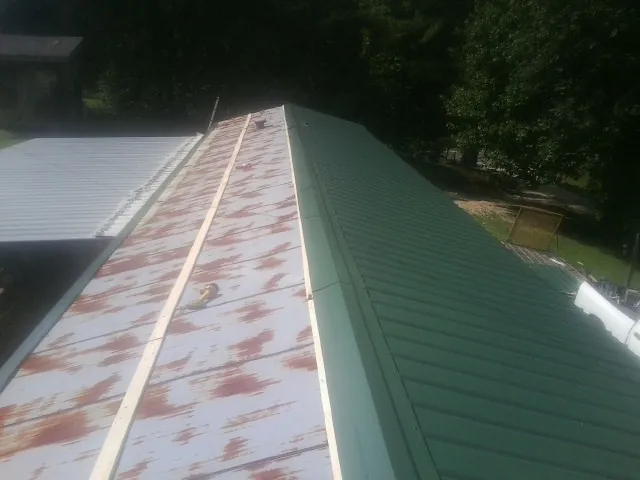 Old rusted panels beside newly installed green metal roofing — Wind Damage Roof Repair by Roofing Brothers in Susan