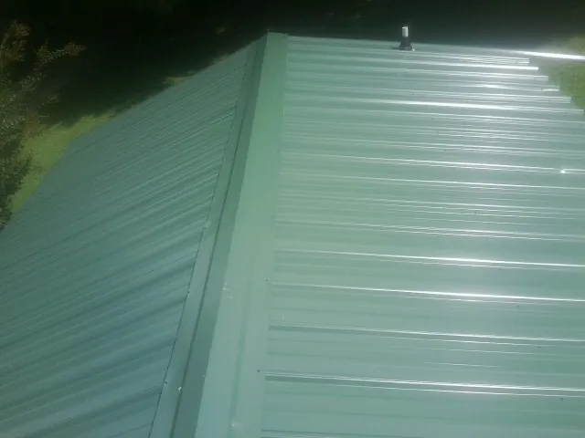New green metal panels meeting at the ridge of a roof — Flat Roof Repair work by our crew in Susan