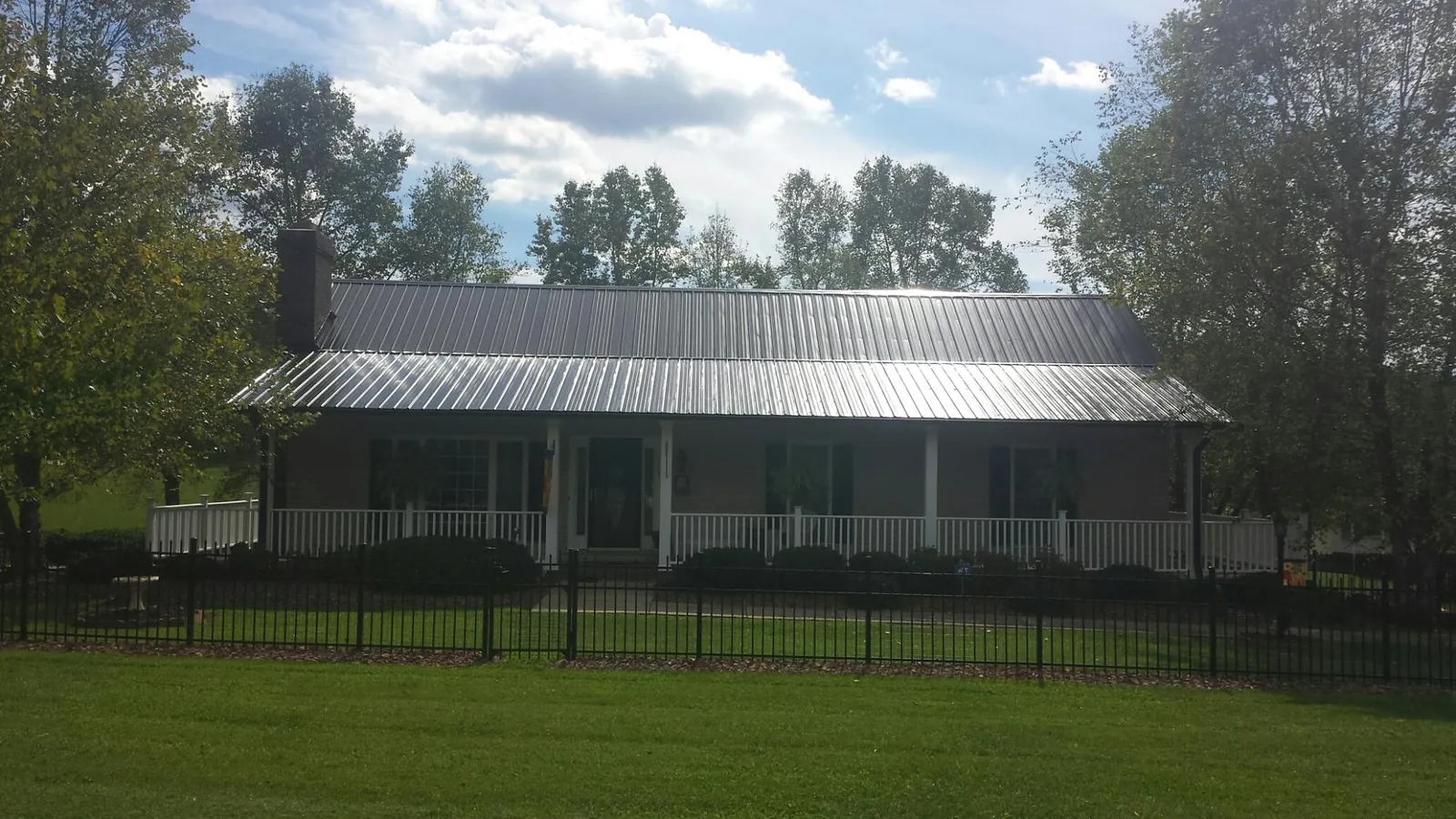 Gray metal roof on a brick ranch with a full width front porch — Gutter Guard Installation work by our crew in Susan