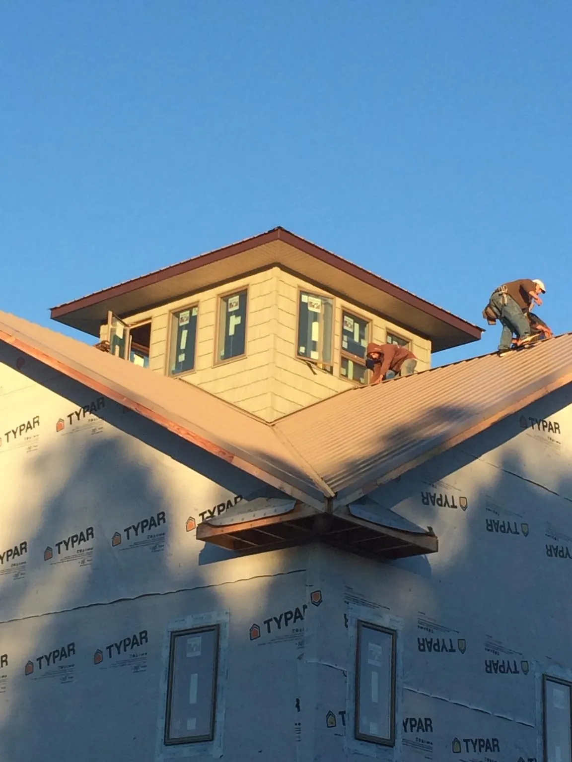 Roofers working around a rooftop cupola on a new metal roof at sunset — Roof Waterproofing in Susan by Roofing Brothers